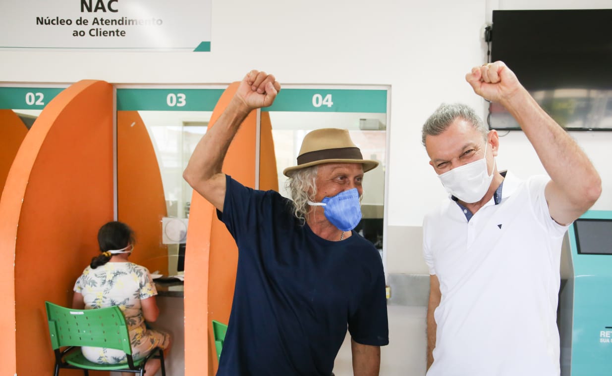 O professor Everardo Viana e o prefeito Sarto, ambos de máscara, vibram após o primeiro ter sido vacinado